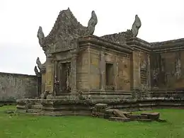 Ruins of a stone building erected on a stone platform. The roof above the main entrance is decorated.