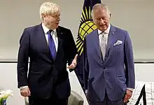 Charles standing next to Johnson with the flag of the Commonwealth of Nations behind them