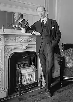 Black and white photo of Prokofiev standing besides a fireplace, his arm rested on the mantlepiece