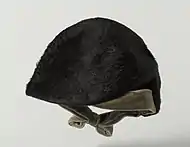 A rounded, furry cap with a velvet bow for securing underneath the wearer's chin.