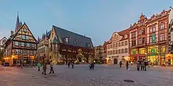 A town square with four visible buildings and a few tourists.