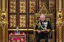 Charles seated on the Sovereign's Throne in the House of Lords during the 2022 state opening of the British Parliament. Next to him is the Imperial State Crown.