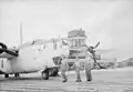 Royal Air Force personnel pass in front of a B-24 Liberator aircraft at Kallang airport, Singapore, in 1945–46