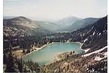 Alpine lake sitting in a basin between snowy mountains