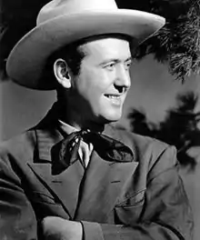 A smiling man wearing a cowboy hat and neckerchief