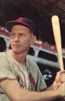 A man in a gray baseball jersey and navy blue cap