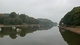 A narrow lake with trees on either side, and boats on the water