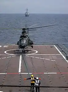 125 Squadron Super Puma takes off from the flight deck of the RSS Resolution – an Endurance-class LST. Visible in the foreground is the Aircraft Ship Integrated Secure and Traverse (ASIST) system.