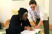 Two people at a table referring to a large book