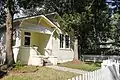 A small yellow house with a white picket fence.