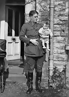 Informal full-length portrait of man in military uniform holding an infant