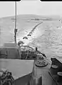 The boom defence net at Scapa Flow being towed into position by two Royal Navy boom defence vessels in 1943.