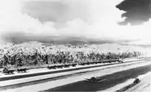 Fighter and bomber aircraft taxi on an airfield surrounded by jungle