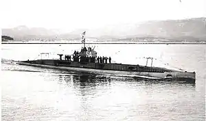 Black and white photo of The Submarine Sané surfaced with people standing on top of the submarine, image was taken in 1926