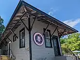 a photograph of the Sag Harbor freight station in its current use as the flagship tasting room for the Kidd Squid Brewing Company, showing a sign affixed to the building's facade with a logo of the Kidd Squid Brewing Company