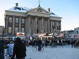 Glass house with sign and spectators, in front of city hall