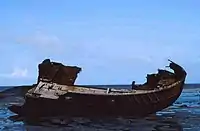 Wooden boat in a derelict state on a calm blue water.