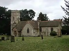 A stone church with a tiled roof and a tower on the left