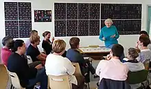 A teacher and student sit opposite one another in a small language classroom