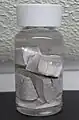 Silver chunks covered be a clear liquid in a sealed bottle