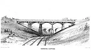 A trestle bridge on four piers spans a cutting over two rail tracks