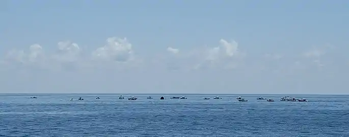 Large numbers of private boats creating a circle around the Endeavour capsule.