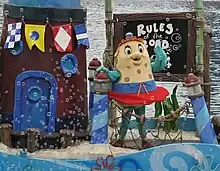 A costumed mascot of Mrs. Puff waving to an audience while standing on a float