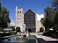 View of St. Andrew's statue, pool, olive trees, and front entrance