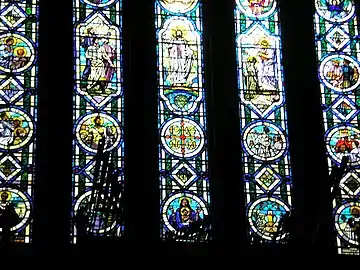 Facing west, silhouette of the organ against stained glass panels in balcony.