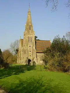 A short stone church with a tall narrow tower and spire