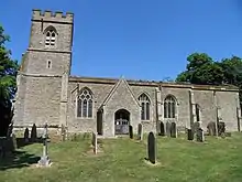 A stone church seen from the south with an embattled tower on the left