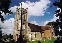 A stone church with a battlemented tower and brick transepts