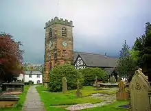 A church with a Gothic stone battlemented tower and a timber-framed body to the right