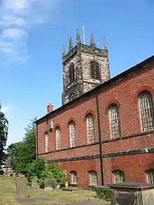 The brick Neoclassical body of a church with a stone Gothic tower behind