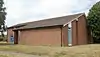 Three-quarter view of a modern L-shaped brick building with a blank wall on the shorter side.