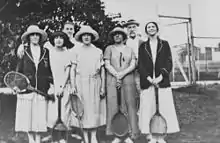 Five women standing with tennis rackets in hand