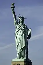 A crowned, robed woman holding aloft a torch