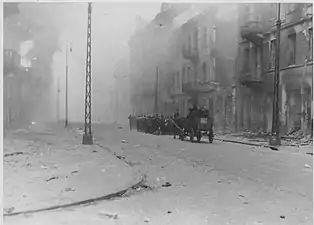 NARA copy #44, IPN copy #44This is how the former Ghetto looks after having been destroyedColumn heading North to Umschlagplatz on Zamenhofa Street, with burning Zamenhofa 25 / Wołyńska 2 on the left.