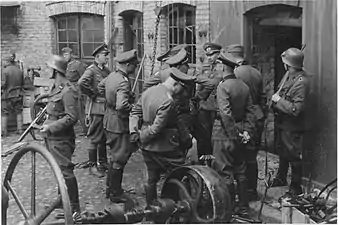 NARA copy #3, IPN copy #3Discussing the evacuation of the factoryThe guard on the left is Josef Blösche. The photo depicts the Herman Brauer helm repair shop at Nalewki 28–38. 24 April 1943