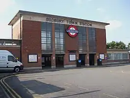 A simple rectangular brick structure with four openings, glass above continues to the roof; the roof is a concrete slab that overhangs the walls.