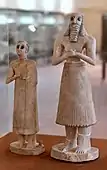 The god Abu (?) and a female statuette; 2800-2400 BC (Early Dynastic period); from the Square Temple of Abu at Tell Asmar (ancient Eshnunna (Iraq)); National Museum of Iraq. The loin-cloth has become recognizably a skirt and the twisted tufts have shrunk to a fringe