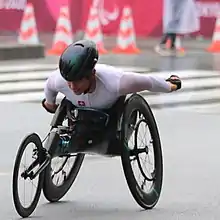 woman in white suit with a small Swiss flag on it racing in her wheelchair