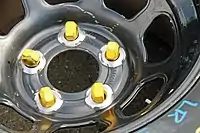 Five yellow lug nuts for use on a car with wheel studs