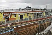 A building with exposed wood and yellow paper, clearly under construction, with a railroad in the foreground