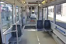 The interior of a streetcar, showing two large windows, hand-holds, buttons, and a short stair leading to an upper section with seating facing forwards and backwards.