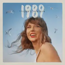 The cover artwork of 1989 (Taylor's Version), showing Swift smiling, seagulls in the background, and "1989" in white and "Taylor's Version" in smaller black above her face.