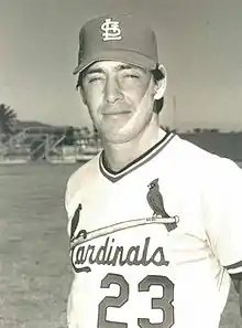 A man in a light baseball uniform and dark cap