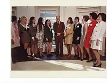 Martha Schwebach (third from the right) meets with President Gerald Ford in the Oval Office, along with the other honorees of the Ten Outstanding Young Women of America award in 1974. The women, five on either side of the president, laugh or smile.