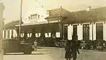 A 1930s photo of the station. Old American cars, people and fruit vendor gather outside the building.