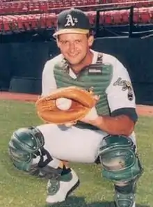 A man in a red baseball jersey with "Sounds" written on the front in white and blue and a blue cap with a white "N" on the center stands on a baseball field swinging a bat.